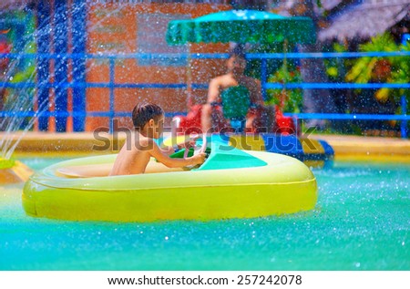 happy kid driving toy water boat in aqua park