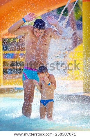 happy excited family under water stream in aqua park