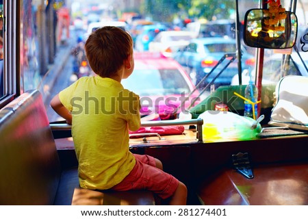 young boy sitting in local public bus, while traveling through the city of Bangkok