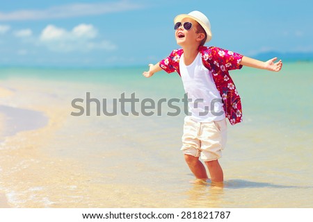 happy fashionable kid boy enjoys life on summer beach