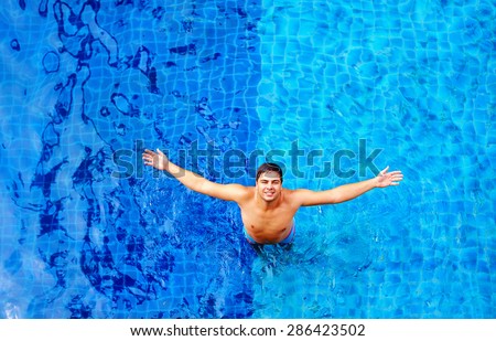 happy man enjoying vacation, while standing in pool water, top view