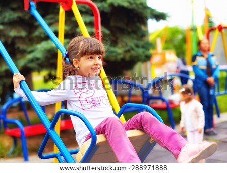 cute happy girl, kid having fun on swings at playground