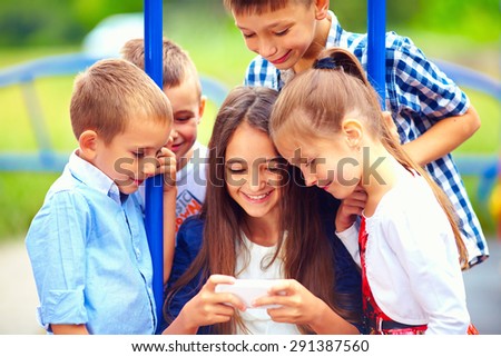 group of happy kids playing online games together, outdoors