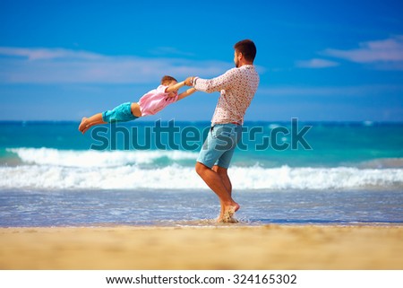 happy excited father and son having fun on summer beach, enjoy life