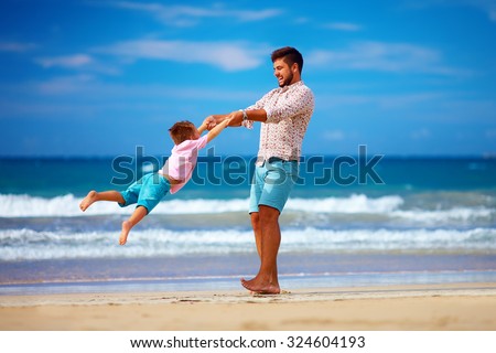 happy excited father and son having fun on summer beach, enjoy life
