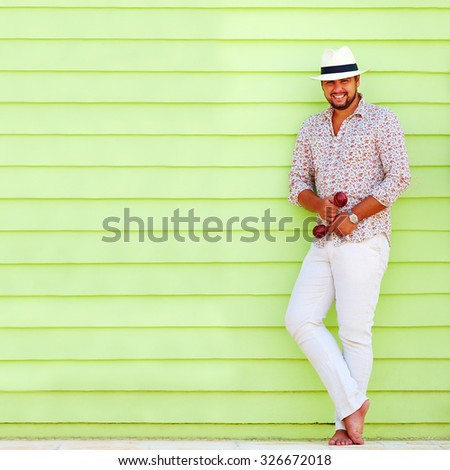 happy man with maraca playing music near the colorful wall