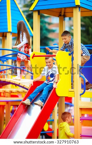 group of happy kids sliding on colorful playground