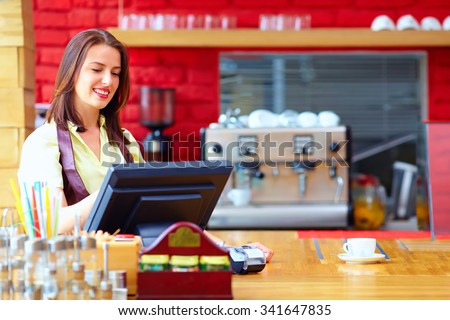 young female cashier operating at the cash desk in cafe