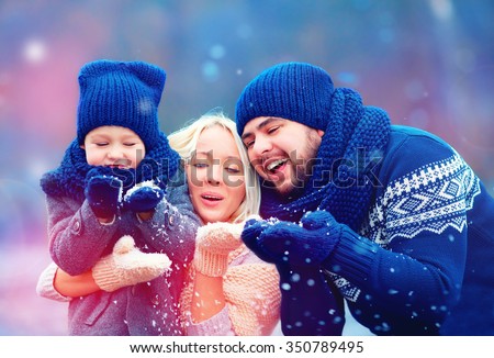 portrait of happy family blowing winter snow