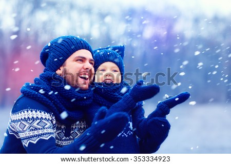 happy father and son having fun under winter snow, holiday season