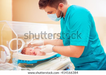 medical staff taking care of newborn baby in infant incubator