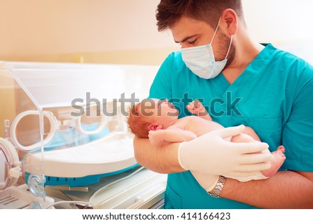young adult man holding a newborn baby in hospital