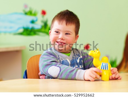 cute kid with down\'s syndrome playing in kindergarten