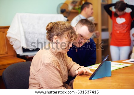two friends with disability in rehabilitation center, watching digital tablet