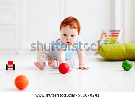 cute infant baby crawling on the floor at home, playing with colorful balls