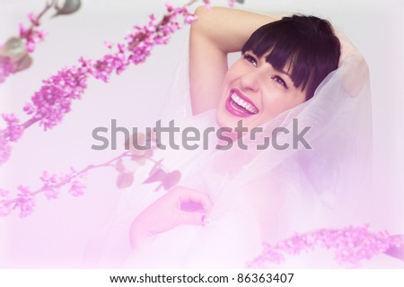 portrait of a beautiful young smiling woman in pink flowers wearing white organza