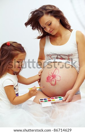 pregnant woman with cute daughter paint mom\'s belly