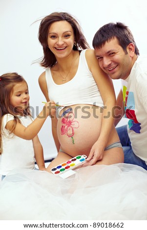 beautiful happy pregnant family of tree are drawing mom\'s belly