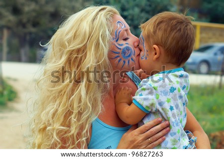 face painted mother kissing her little child