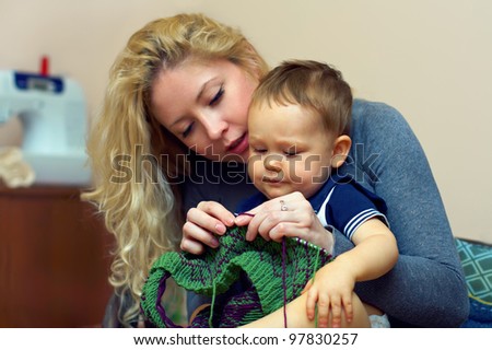 attractive young mother teach her little baby boy knitting, inside home