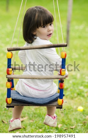 little girl riding on a swing on a green background
