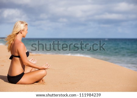 Beautiful Blonde sitting in the Quiet of the Beach ending Meditation with Namaste