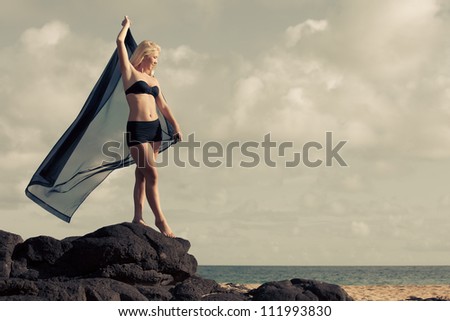 Beautiful Woman on Lava Rocks at the Ocean with a sheer blowing in the wind