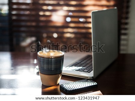 Morning sun shining on computer and coffee with dust in the air