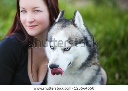Beautiful Siberian Husky dog outdoors with his woman owner behind him