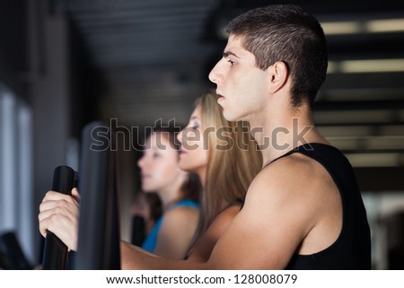 Attractive muscular man exercising with women at the gym