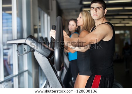 Attractive muscular man exercising with women at the gym