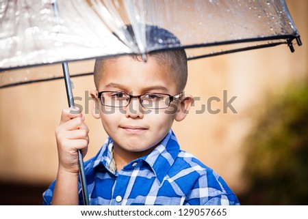 Cute young boy in the rain on a sunny day with umbrella