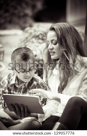 Mother and son together on Mother\'s day reading from a touch pad black and white image