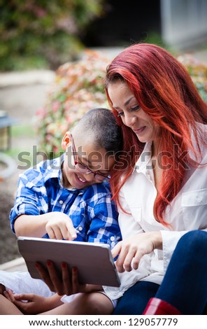 Mother and son together on Mother\'s day reading from a touch pad