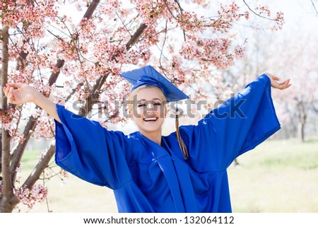 School Graduation Pretty Blonde woman in cap and gown arms outstretched