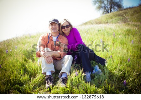 Attractive Middle Aged Couple Lying In The Tall Grass And Wild Lupine