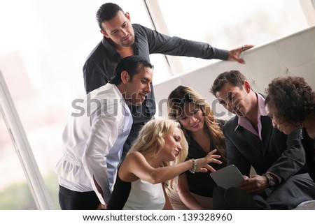 Group of young diverse ethnicity people getting together after a party looking at pictures on a  touch pad