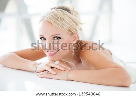 Gorgeous smiling blonde bride  in front of a Penthouse window at a modern hotel