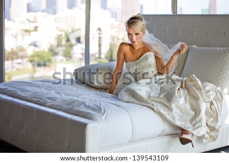 Beautiful Blonde Bride on a Bed at a hotel