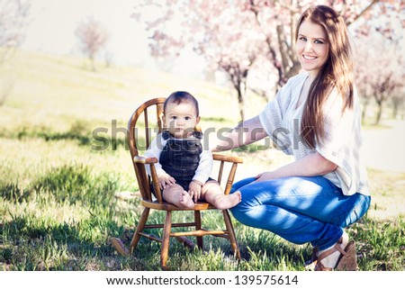 Beautiful Mother and her Baby boy in a rocking chair under cherry blossoming trees