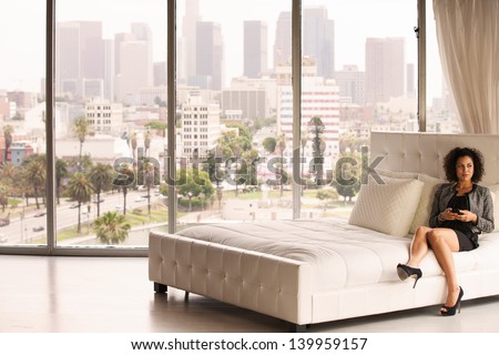 Beautiful Business Woman in a Penthouse Suite at a Hotel on her cell phone