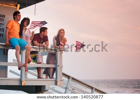 Young Group of Friends at the Beach at Sunset with American Flags