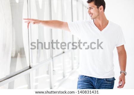 Attractive Guy pointing out the window as he is walking through a Penthouse