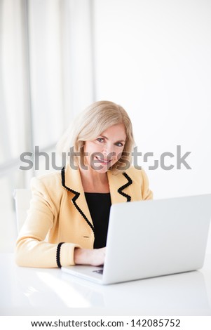 Attractive Middle Aged woman writing her blog  on a computer