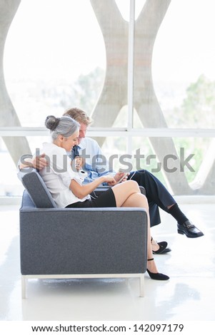 Attractive Mature Couple enjoying music together on a Mini Pad at a Modern Hotel in Los Angeles