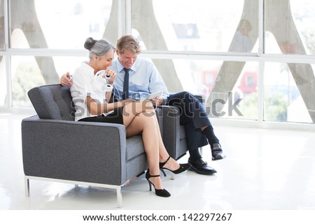 Attractive Mature couple listening to music on Headsets from a Mini touch Pad