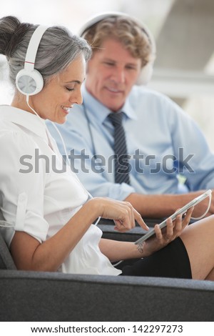 Beautiful Mature woman sharing music off a mini touch pad with her spouse