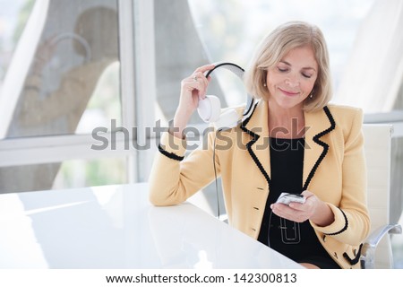 Beautiful fifty year old woman enjoying music with her noise canceling headset