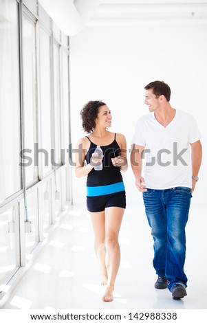 Beautiful woman drinking iced cold water after her work out while walking with a guy