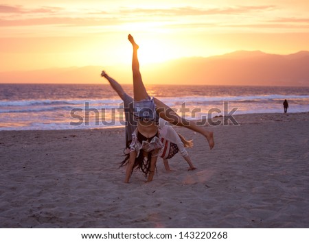 Sunset with Two Beautiful Women doing cartwheels on the Beach in Santa Monica California